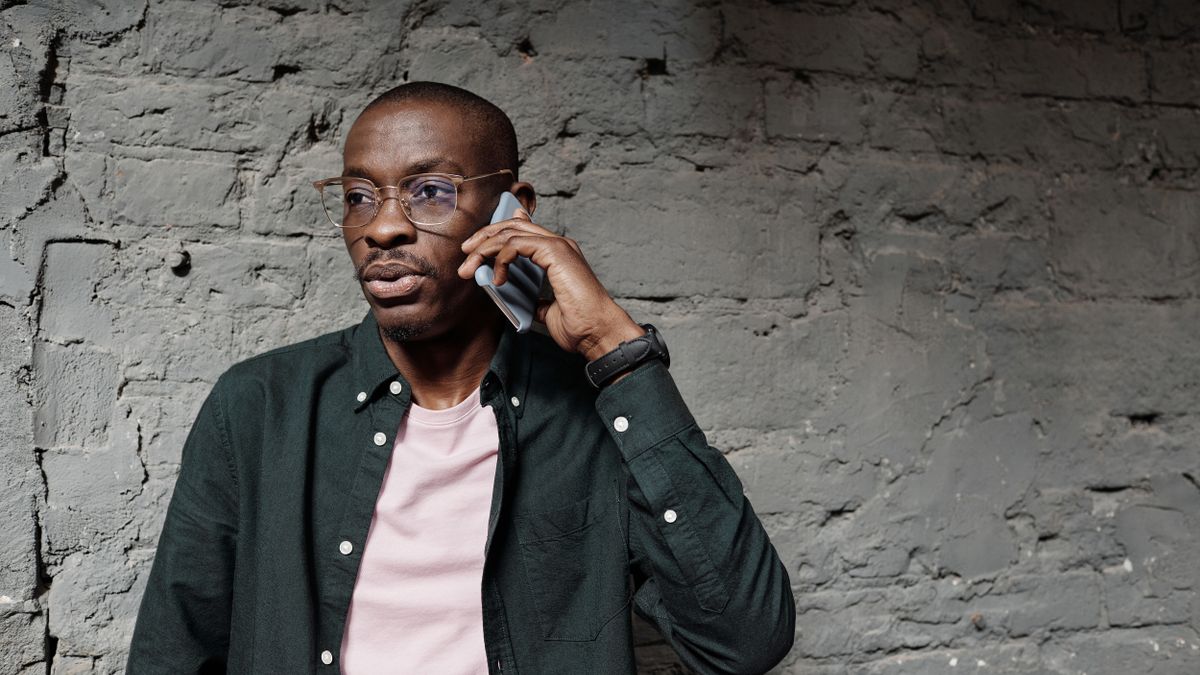 Man on a call against a brick wall