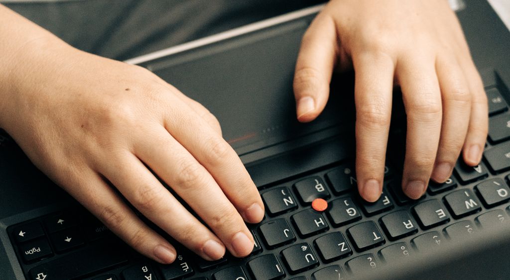 Hands typing on a laptop keyboard in close up