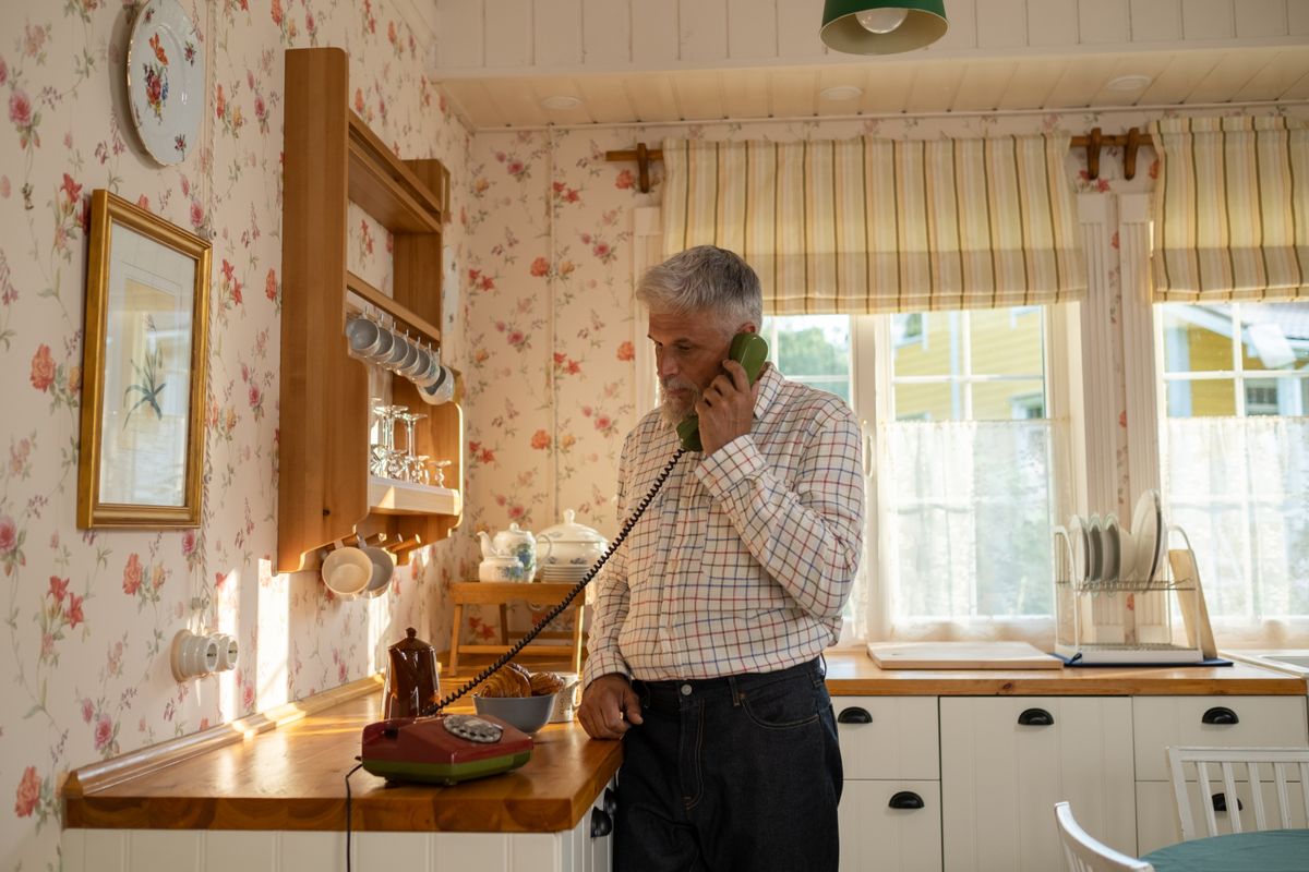 Man making a call on a home phone in his kitchen
