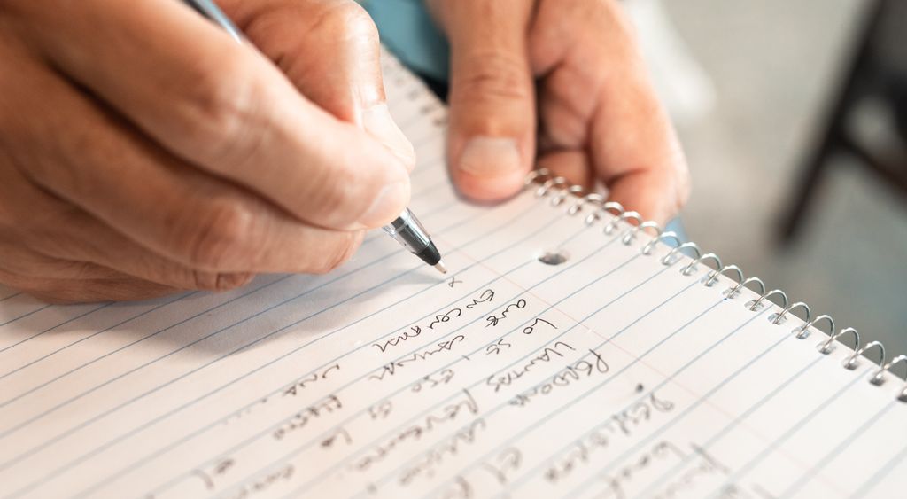 Hand writing language practice notes in a spiral notebook
