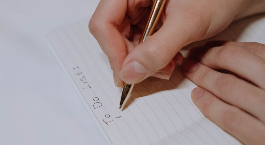 Hand writing a to-do list on a lined notebook page
