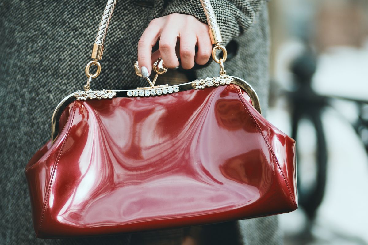 Woman holding a red patent designer handbag