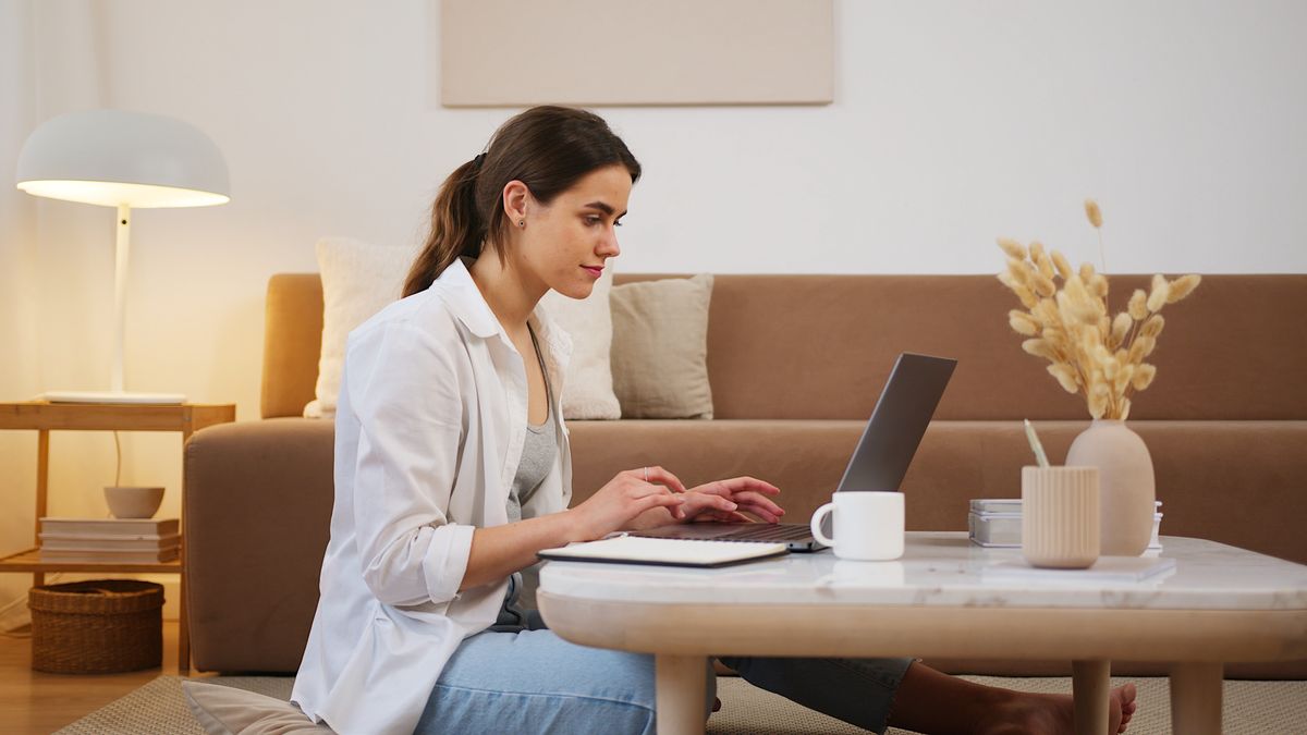 Woman working on a laptop at a coffee table in a rented living room